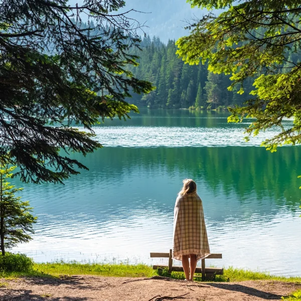 woman-in-blanket-looking-at-beautiful-black-lake